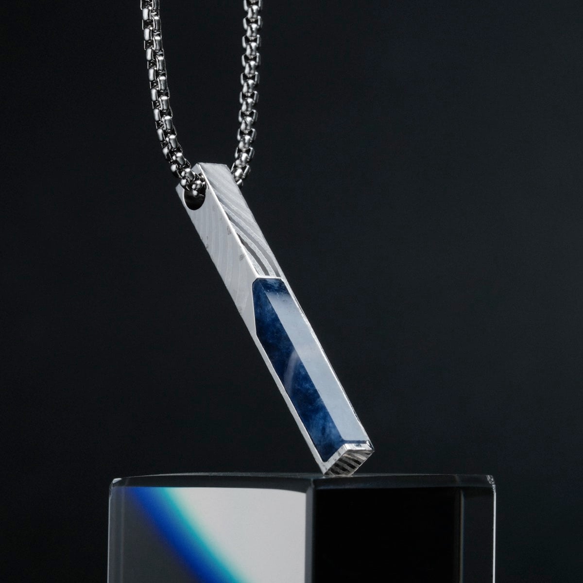 "Campania Necklace" necklace featuring a sleek sodalite and Damascus design on a dark background.