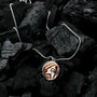 "Operazioni Collana", una collana elegante con un ciondolo in argento e jasper, posato su pietre con texture scura.