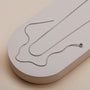 "Charms Bracelet", a sleek and elegant silver necklace, displayed on a minimalist beige background.
