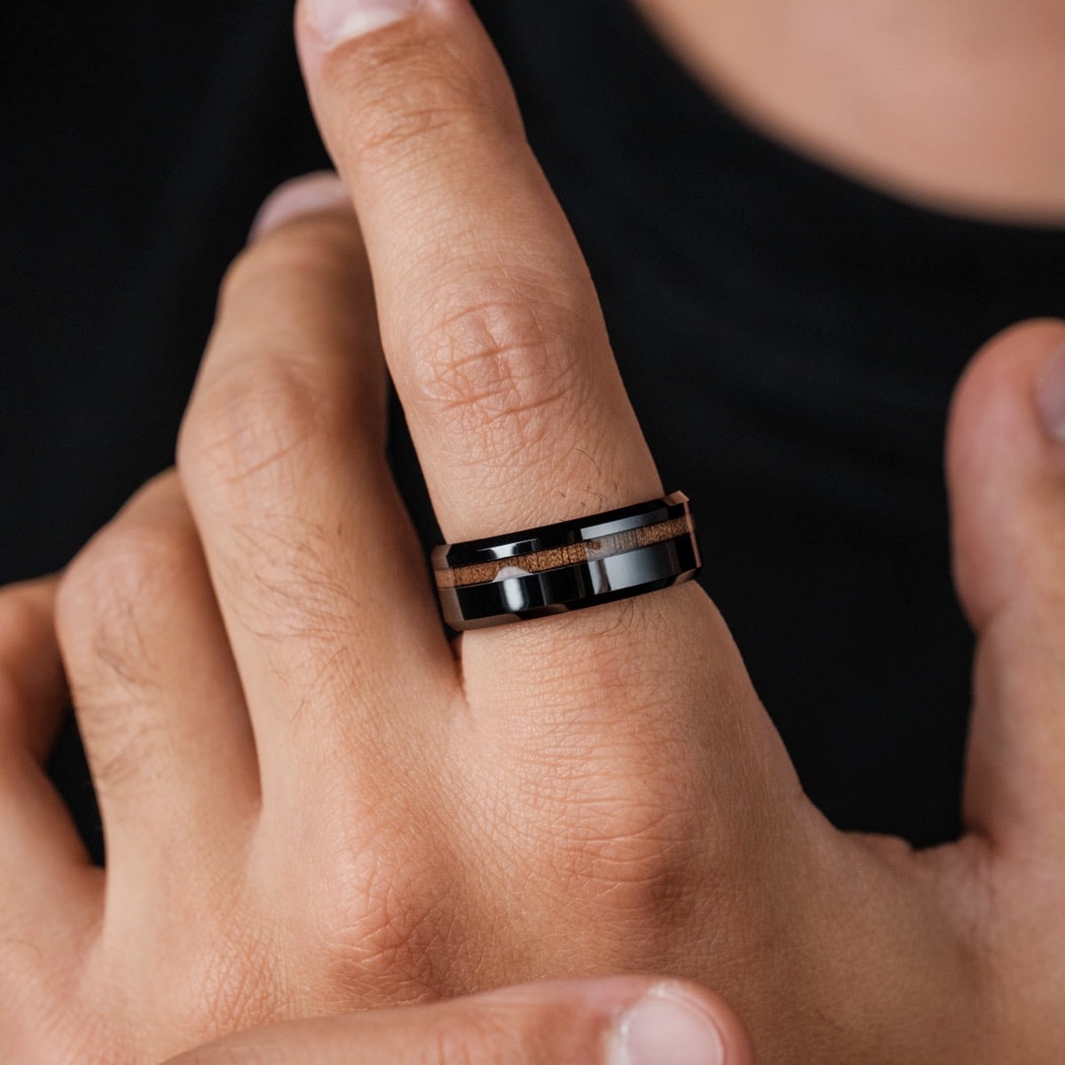 "Sumo Ring", a modern ring with walnut and ceramic accents, displayed on a finger.