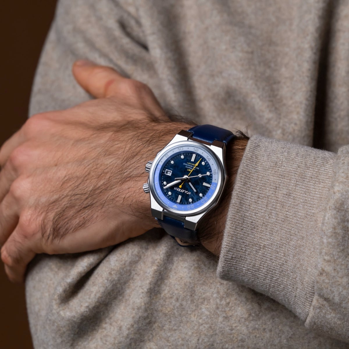 "GMT Cloudhopper" watch, featuring a marble and blue color design on the wrist of a person in a beige sweater.