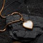"Collana di Amorance", una collana elegante con un pendente a forma di cuore e catena in oro rosa su uno sfondo scuro texture.