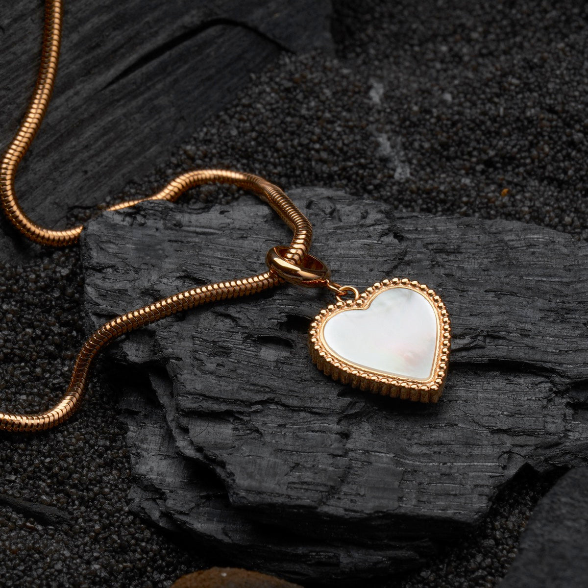 "Collana di Amorance", una collana elegante con un pendente a forma di cuore e catena in oro rosa su uno sfondo scuro texture.