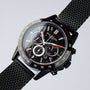 L'orologio "Comfort Crusher" presenta un elegante marmo e un design nero con una fascia in maglia e un volto cronografo dettagliato.