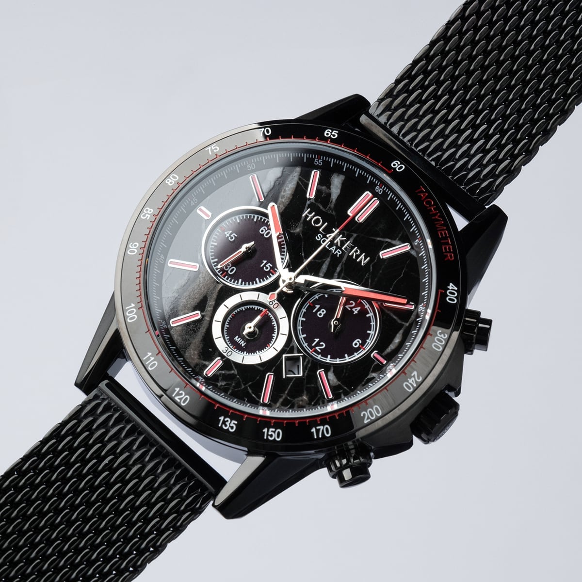 L'orologio "Comfort Crusher" presenta un elegante marmo e un design nero con una fascia in maglia e un volto cronografo dettagliato.