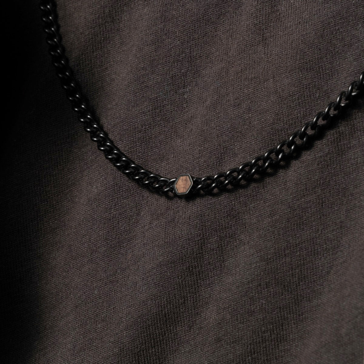 "Bodyguards Necklaces" necklace, featuring a blend of walnut and antique silver, shown with a dark, textured backdrop.