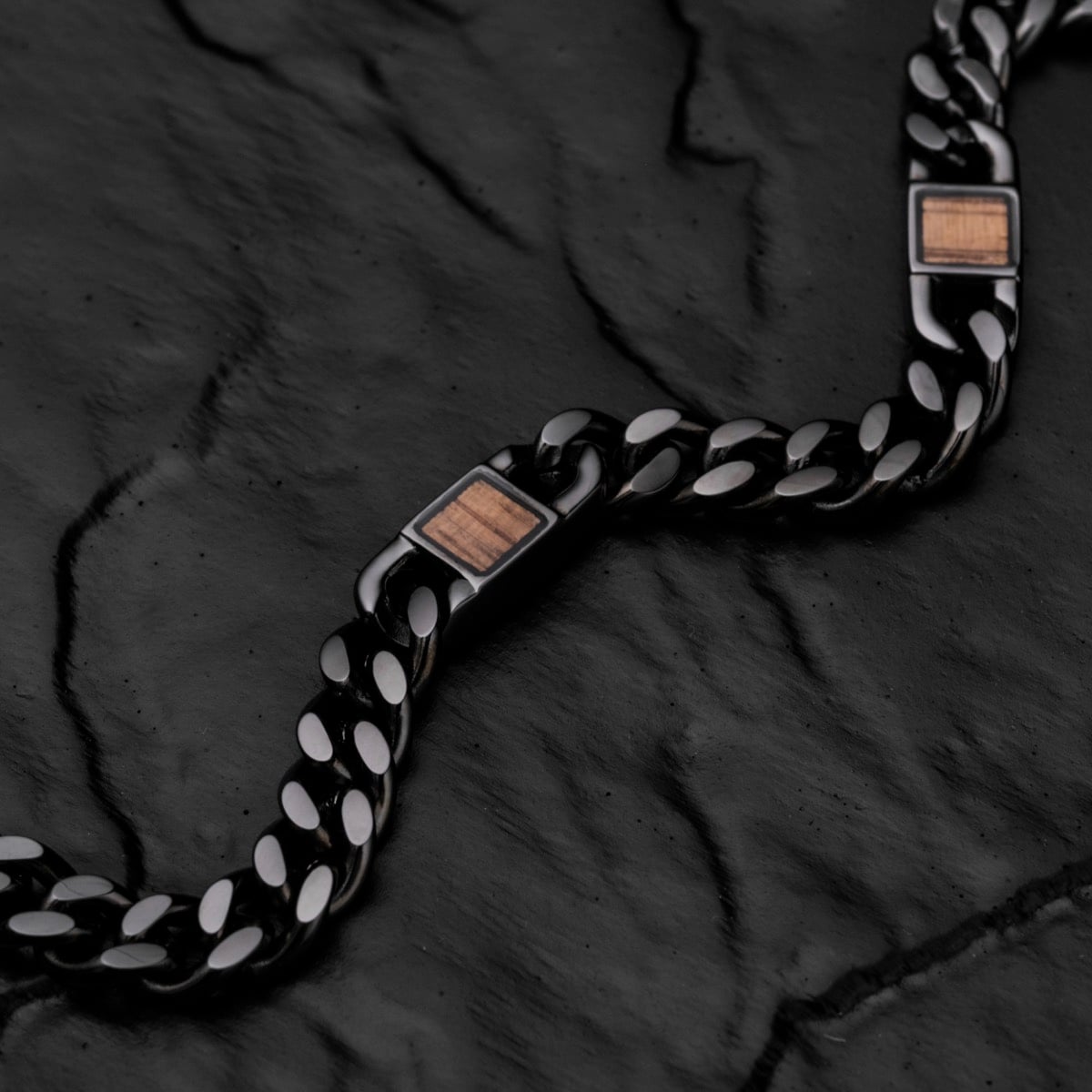 Cinturino "Bodyguards Strap" con accenti in noce e uno stile grigio scuro, posato su una superficie nera texture.
