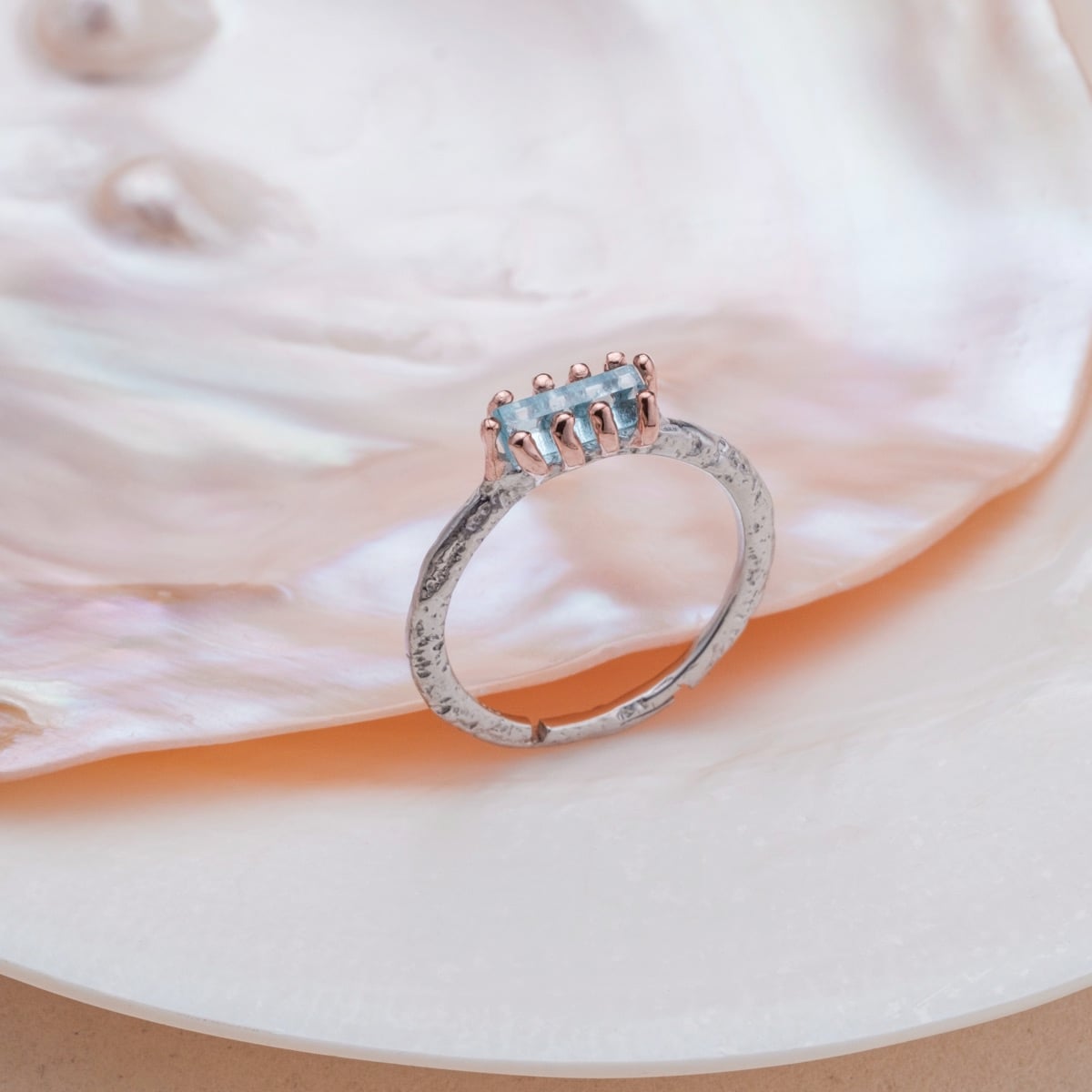 Anello argentato realizzato in oro acquamarina e rosa con uno stile elegante e texture.