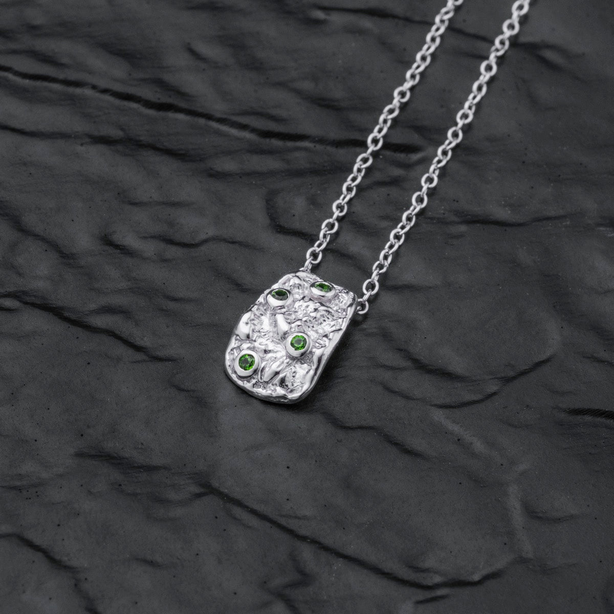 "Silverstream Necklace is a stylish silver necklace featuring green diopside stones on a textured pendant design."