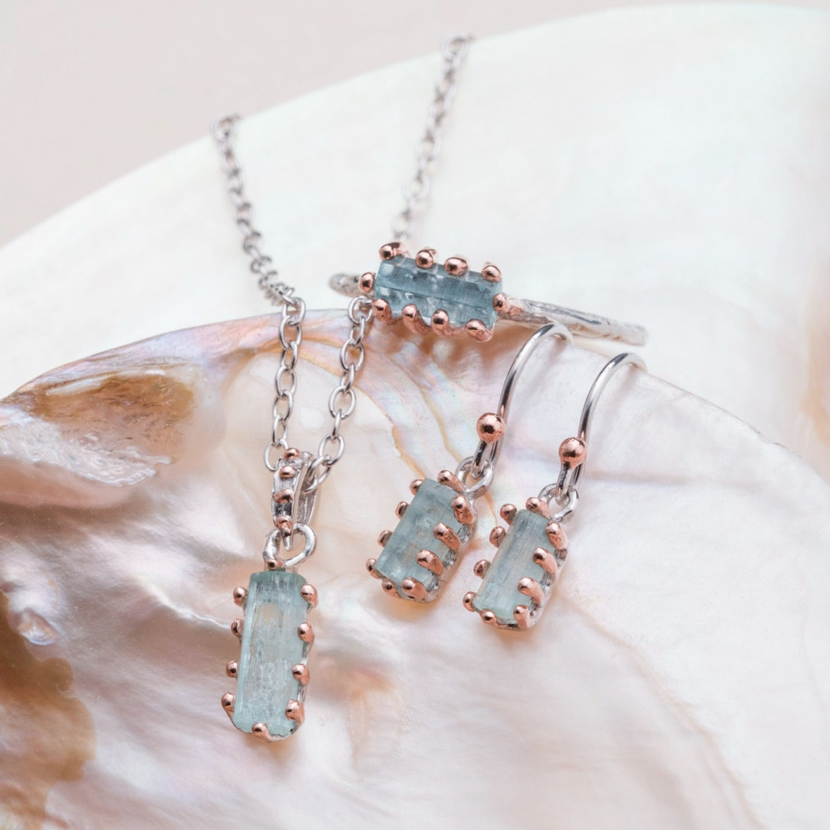 "Silverstream Earrings, elegant earrings featuring aquamarine stones and rosegold accents on a delicate setting."