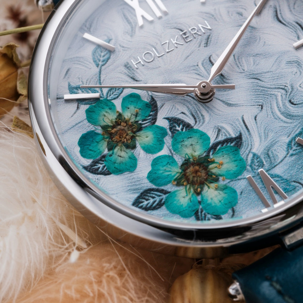 Orologio "Everbloom" con un design floreale blu vibrante con accenti di fiori di prugne e dettagli eleganti in argento.