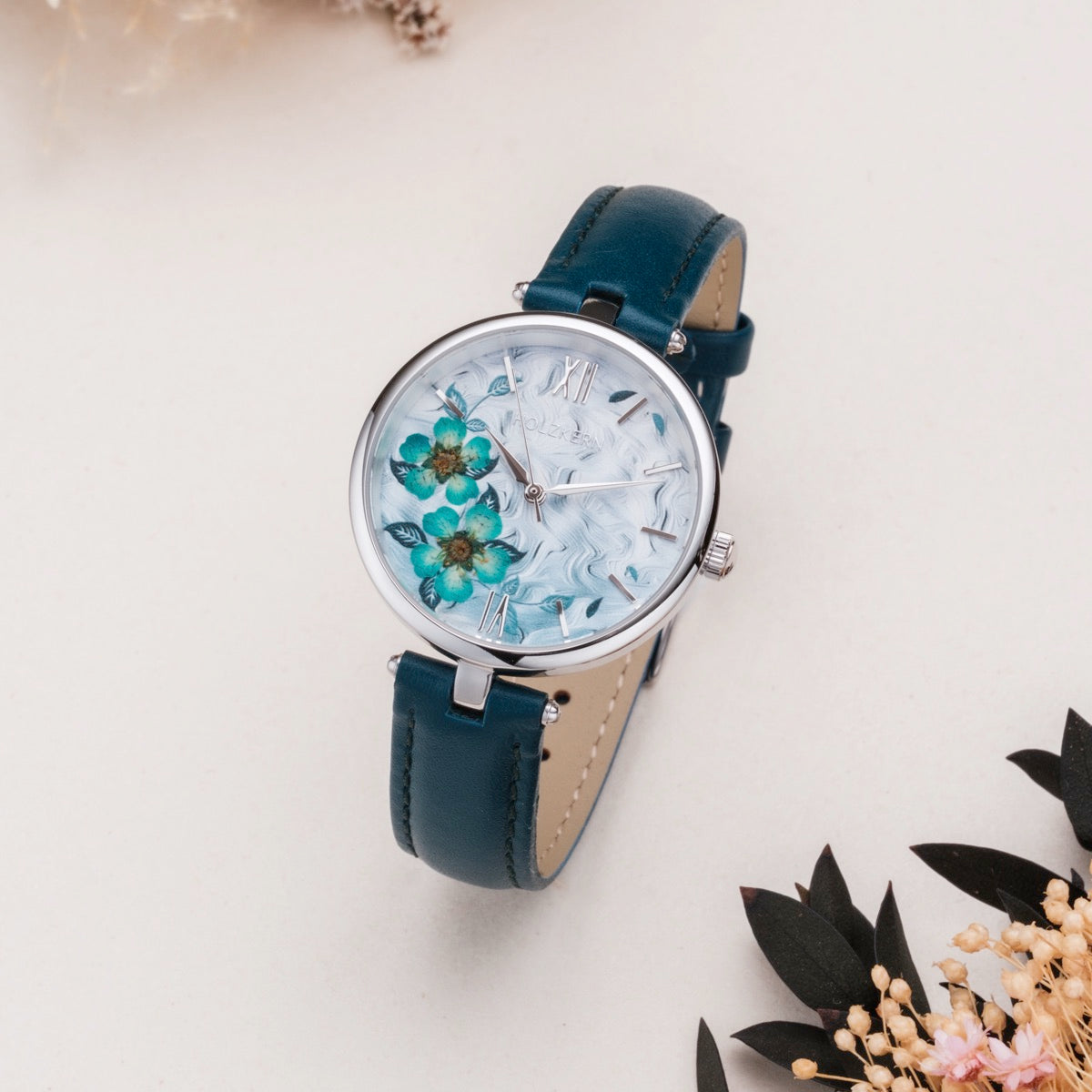 Orologio "Everbloom" con un design floreale susina con cinturino in pelle blu e quadrante floreale intricato.