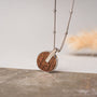 "Collana di città": una collana elegante con un ciondolo circolare in noce e argento su una catena elegante.