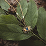 "Collana di danza", una collana d'oro con un ciondolo Lapis Lazuli, mostrata su fondo fogliare.