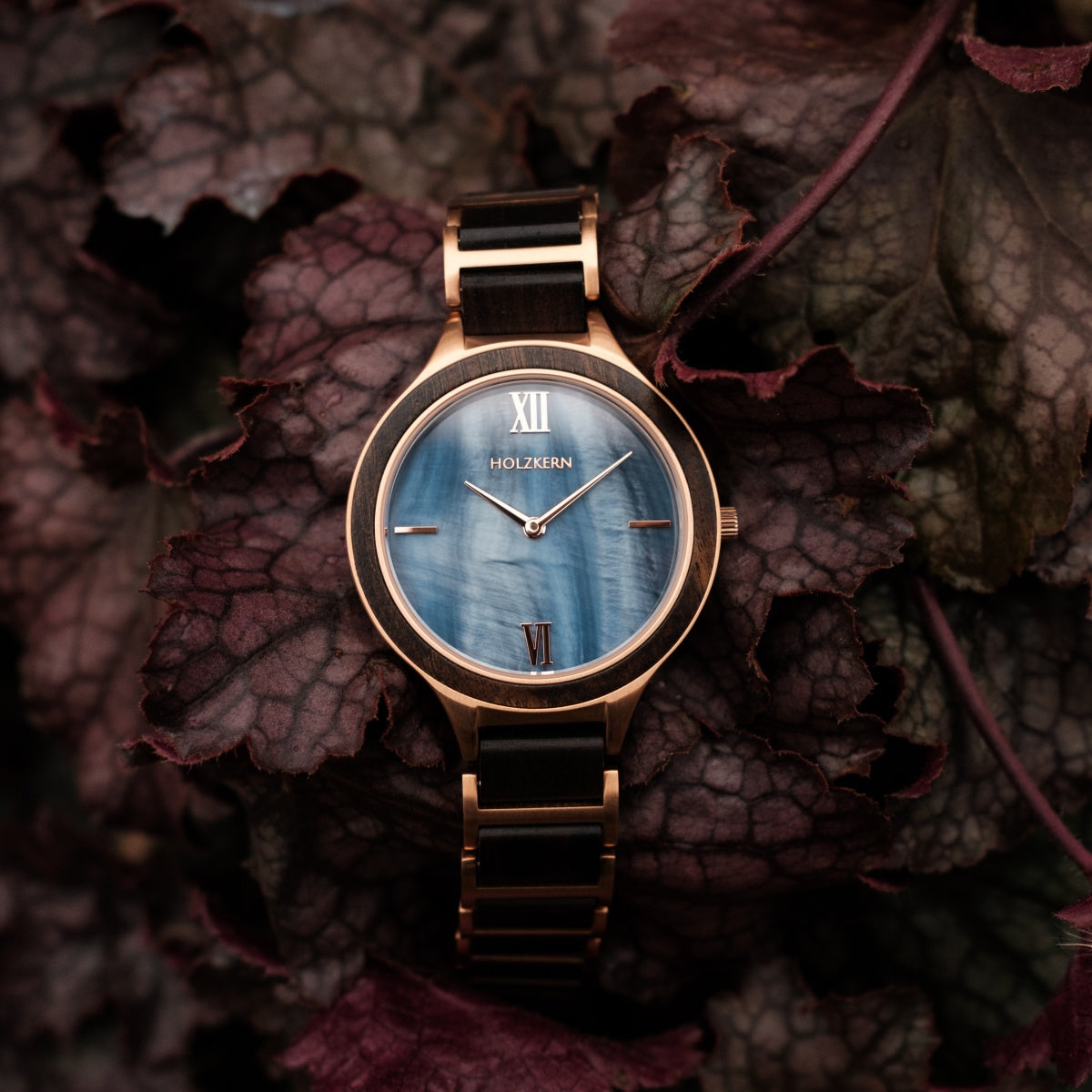 "Maui" watch featuring a maple wood and nacre design on a dark, textured background.