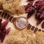 "Mauritius" watch featuring a sleek wood and nacre design, surrounded by amaranth foliage for an elegant look.
