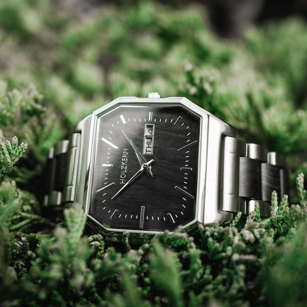 Orologio "Kéré", dal design elegante e dal design acero, incastonato su uno sfondo naturale vibrante.