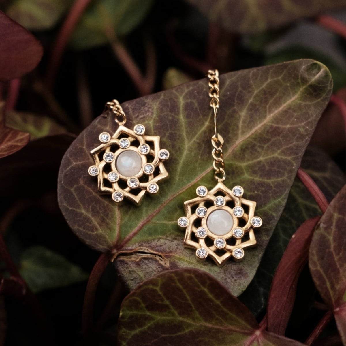 "Composition Gem Earrings": Elegant gold earrings featuring moonstone and a symmetrical gem design.