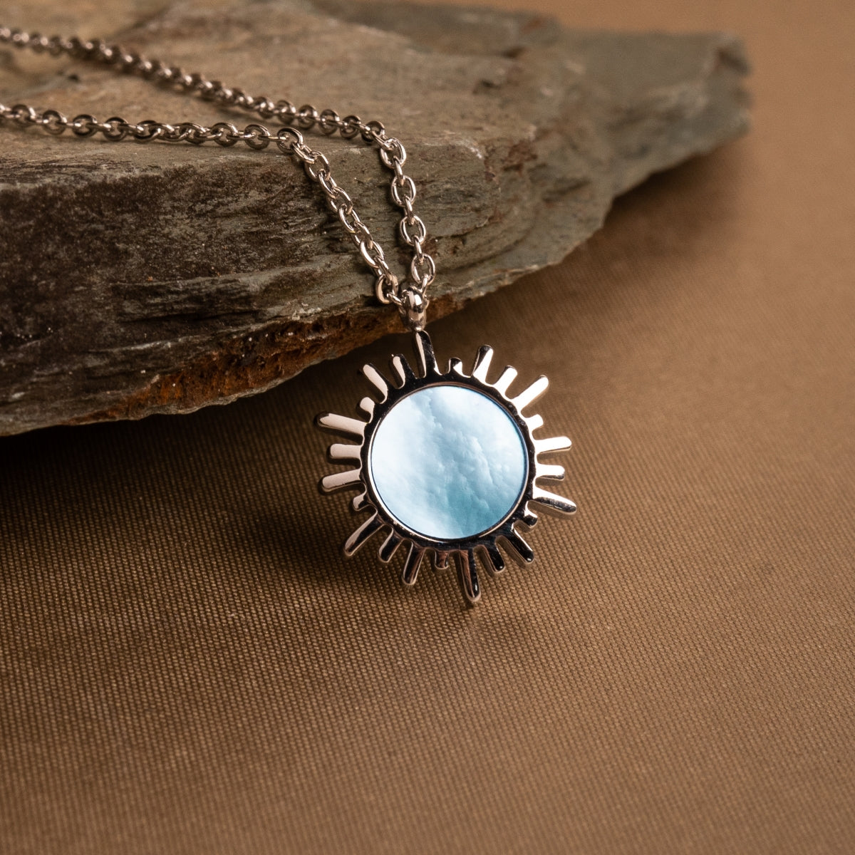 "Shade Necklace", a necklace featuring a sunburst design with blue nacre and silver.