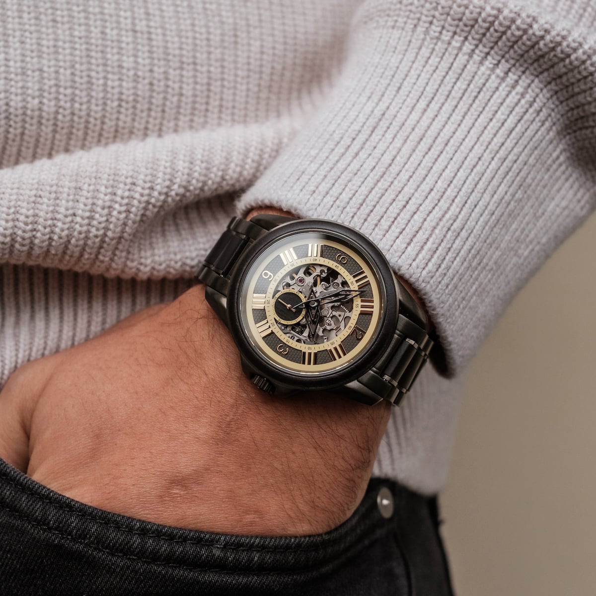 Orologio "Navona" con un design elegante e nero con quadrante acero, indossato contro un maglione con texture.
