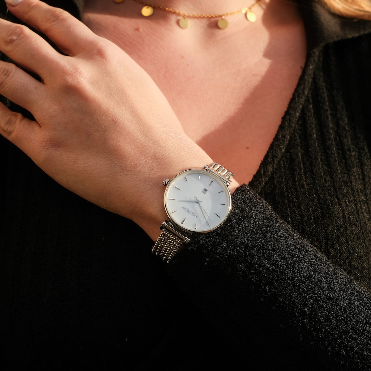 "Piccolo" elegant watch, nacre face with silver accents and mesh band, worn on wrist.