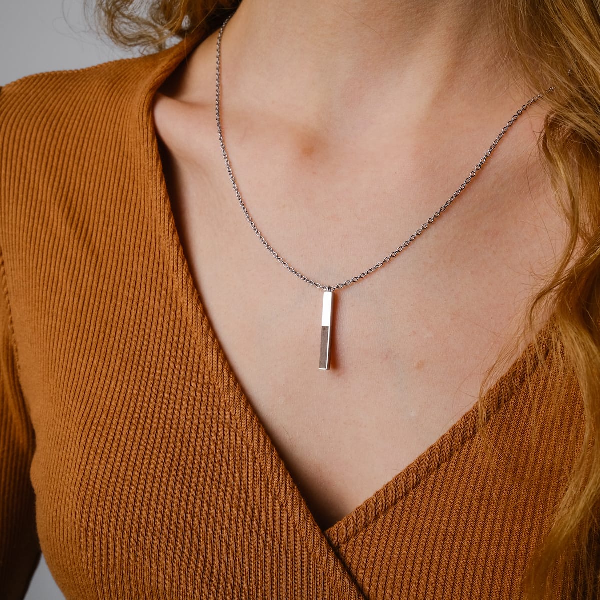 "Campania Necklace" necklace featuring a sleek walnut and silver design, elegantly styled on a textured brown background.