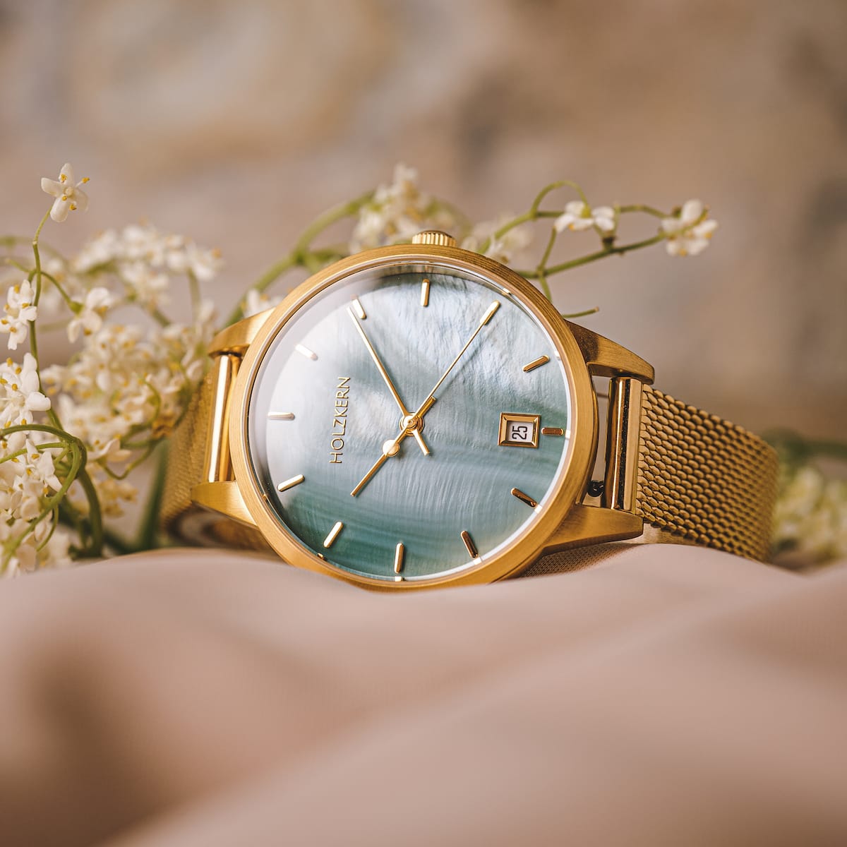 Orologio "Talamanca" con quadrante e fascia in mesh oro, circondato da fiori delicati per un look elegante.