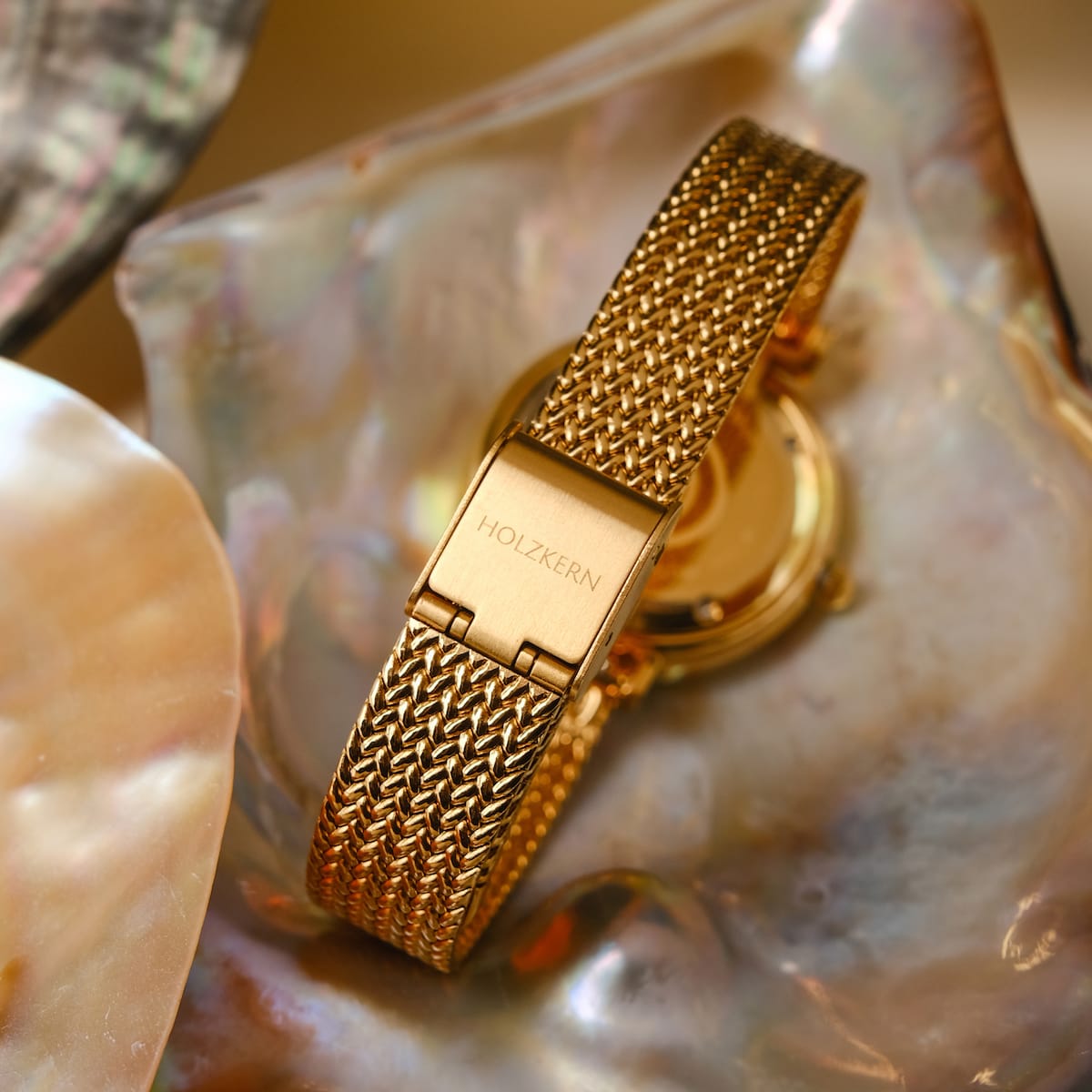 "Giggles" watch featuring a nacre and gold design with an elegant mesh band.