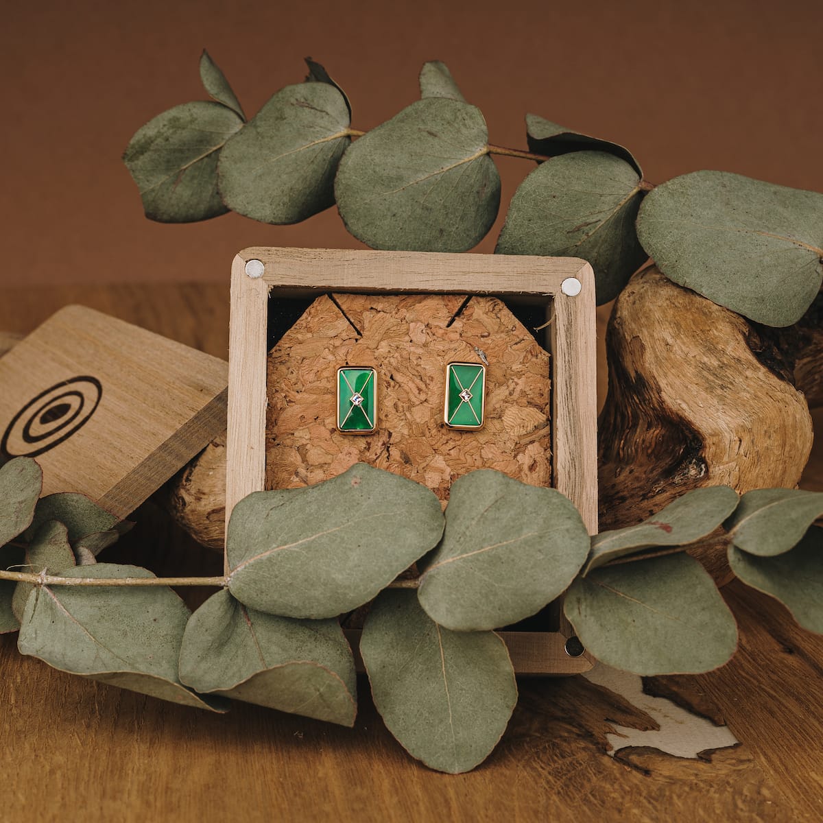 "Aquarell Orecchini", eleganti orecchini con uno stile verde rettangolare in oro, incastonato in un display a tema legno.