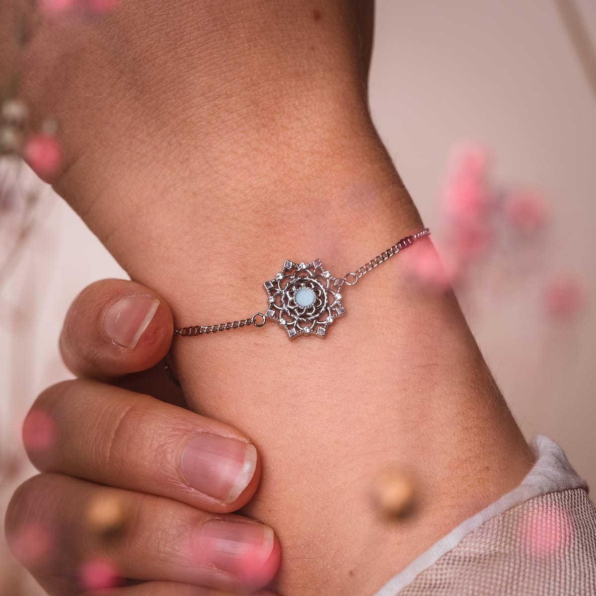 Bracciale "Aphonia" in acquamarina e argento, con un design floreale intricato su un polso delicato.