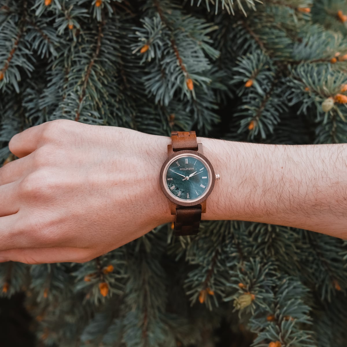 Orologio "Nymph" con fascia di noce e faccia in marmo, che mostra elegante design naturale su uno sfondo di pino.