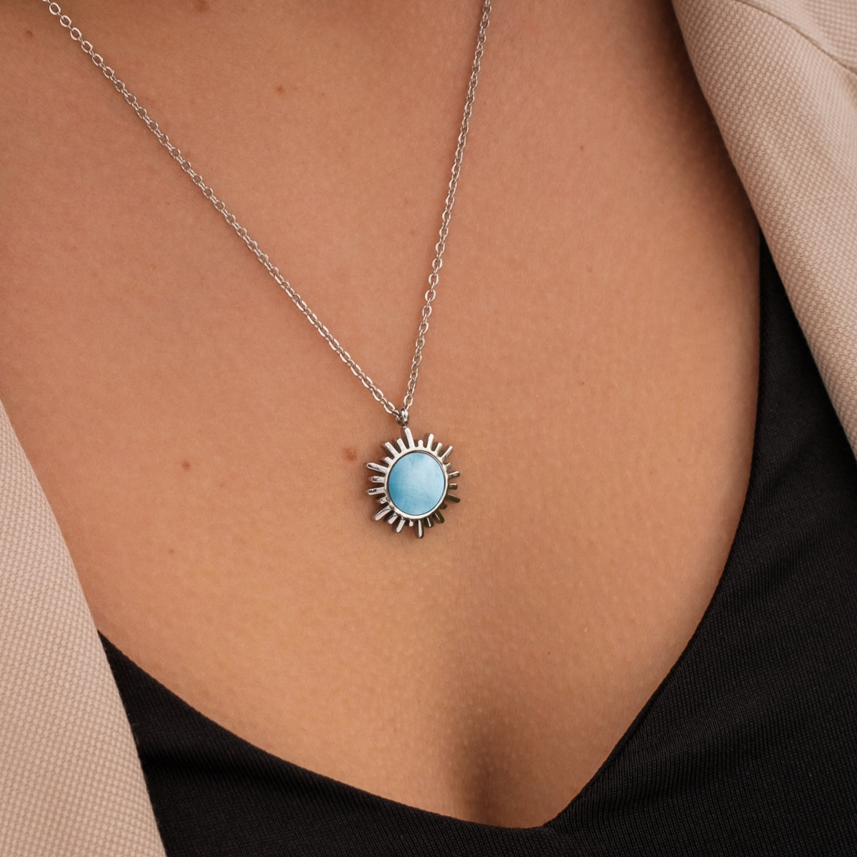 "Shade Necklace" necklace, featuring a blue nacre pendant with a silver sunburst design on a delicate chain.