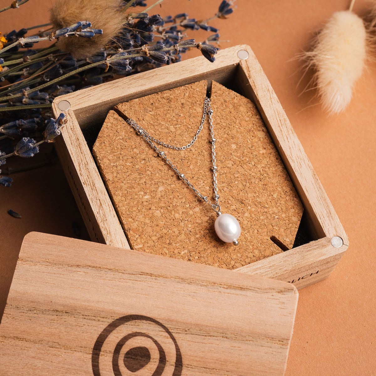 "Panoramic Necklace": elegant silver necklace with a white pearl, presented in a rustic wooden box.