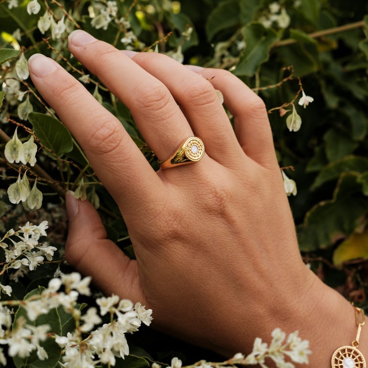 "Pixa Ring": Elegante anello in oro con dettagli bianchi in mezzo al verde rigoglioso.