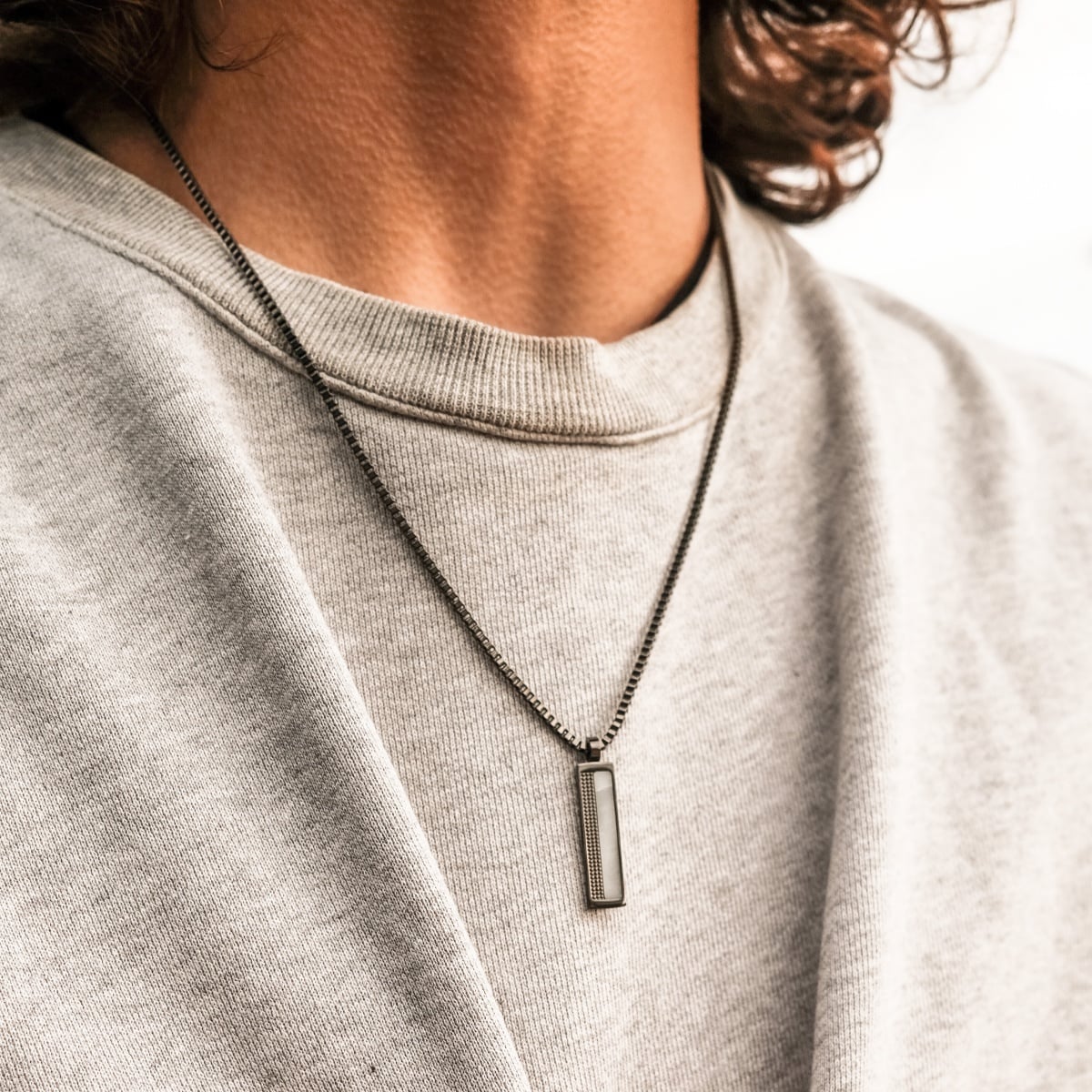 Collana "Planarity Collana", con stile marmo e grigio scuro, elegantemente indossata su una felpa neutra.