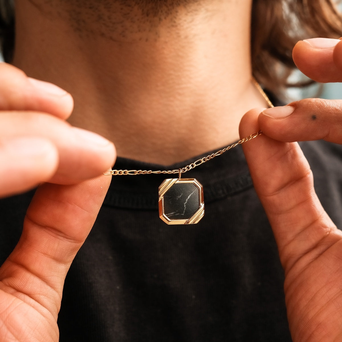 Collana "Scalar Collana" con un design in marmo e oro elegantemente eroe da una persona.