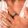 Stylish "Numerary Ring" ring featuring a maple and gold design, worn on a person's index finger for a classic look.