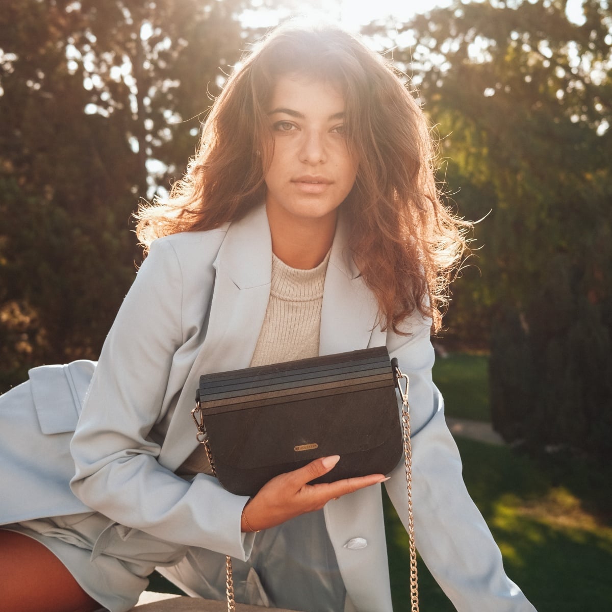 "Iveya VEGAN Black Slate, a vegan handbag, features a sleek black slate design with a stylish gold chain strap."