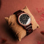 Orologio "Passion" con disegno Padauk e Maple, con una fascia in legno e quadrante elegantemente su un fondo di cuscino texture.