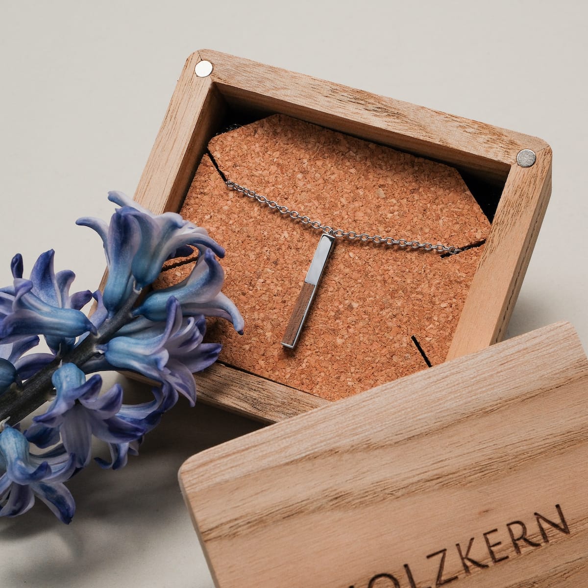 "Campania Necklace" necklace, featuring a pendant in walnut and silver, elegantly displayed in a rustic wooden box.