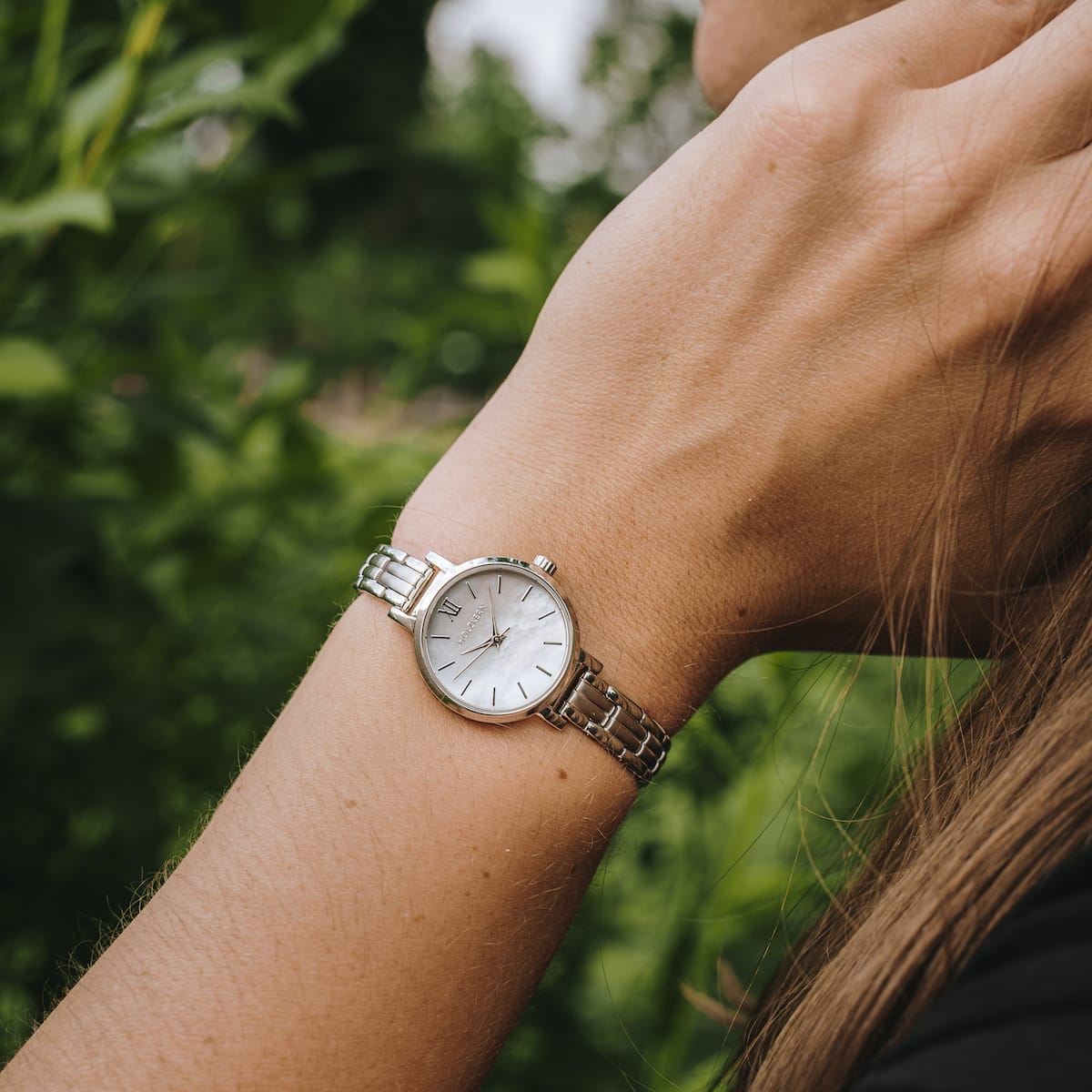 "Skadi" watch with nacre dial and silver bracelet in elegant outdoor setting.