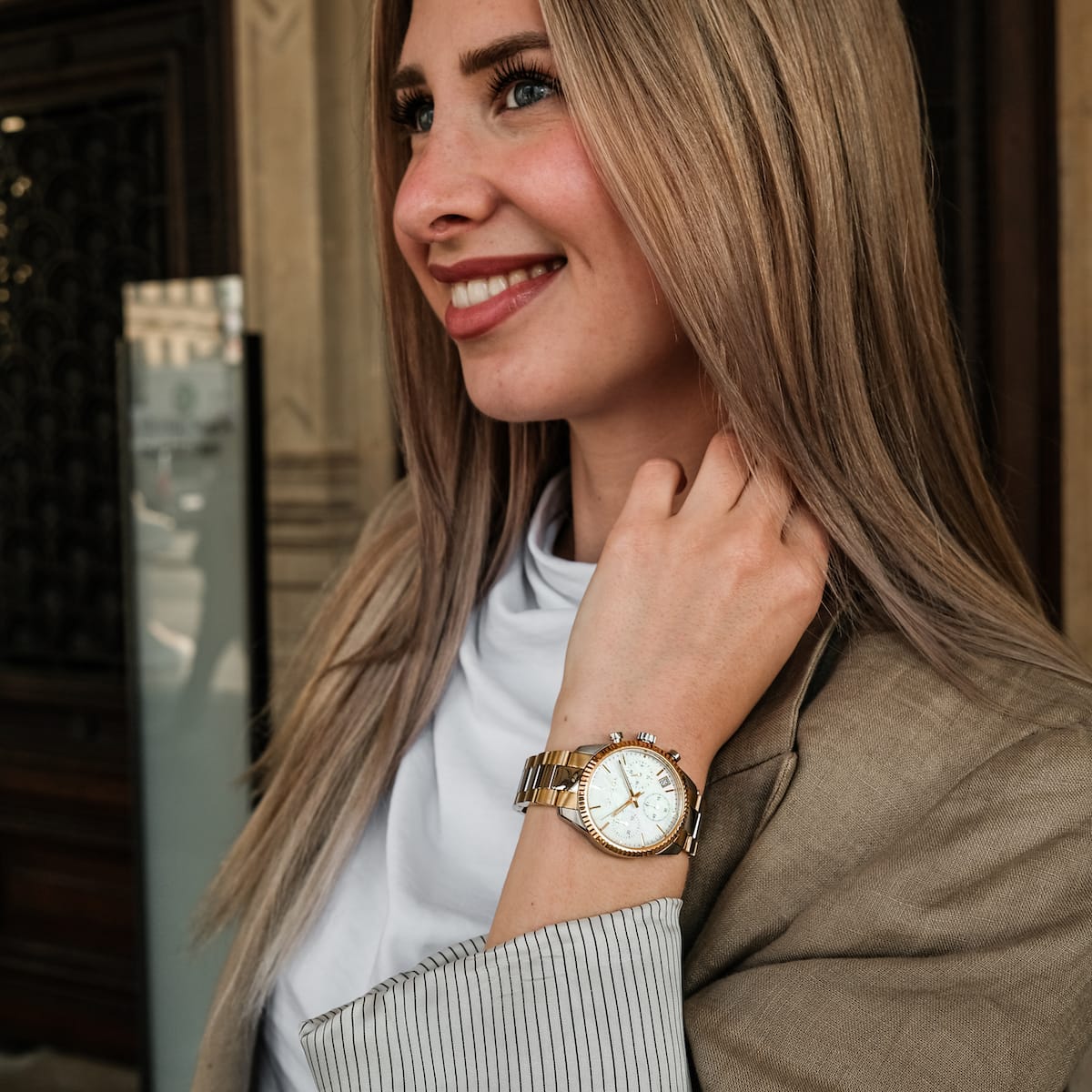 "The Supportive", un orologio elegante con finitura nacre e oro, indossato da una persona sorridente in abbigliamento professionale.
