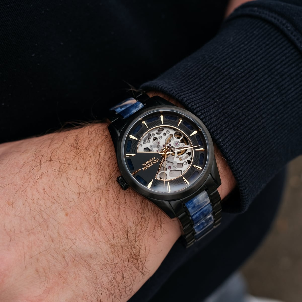"Vredefort" marmo e orologio nero che mostra un design elegante e aperto con accenti d'oro.