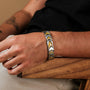 "Command" bracelet featuring a jade and silver chevron design, worn casually on a wrist.