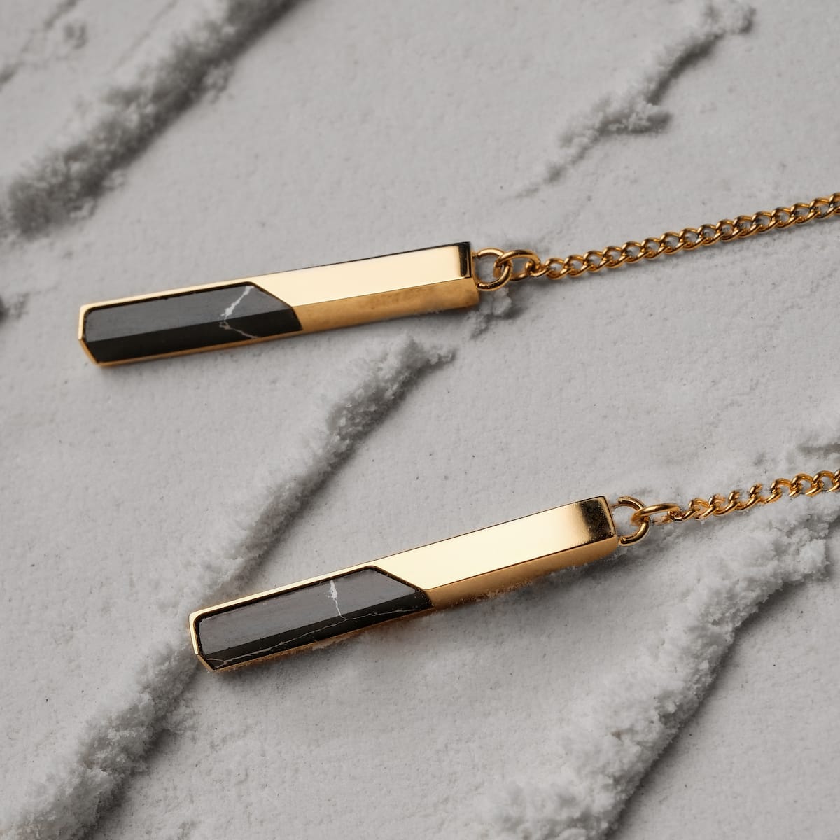 "Campania Earrings earrings feature a sleek marble and gold design, showcasing elegant rectangular pendants on a chain."