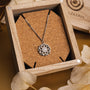 "Composition Gem Necklace", a silver necklace featuring a moonstone pendant with intricate design in a rustic wooden box.