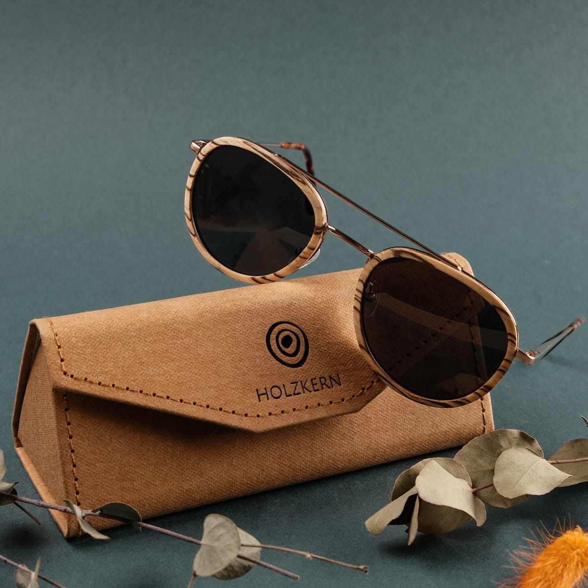 Occhiali da sole "The Risky" con cornici Zebrawood e accenti in oro opaco, visualizzati con un caso elegante.