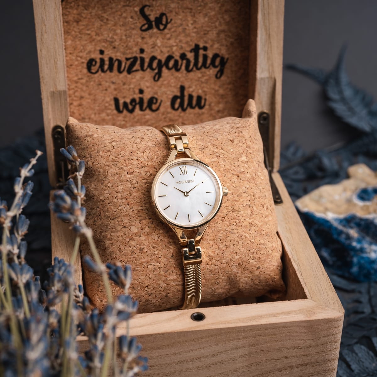 Orologio "Kaliya" con disegno in oro e grigio, elegantemente esposto in una scatola di legno.