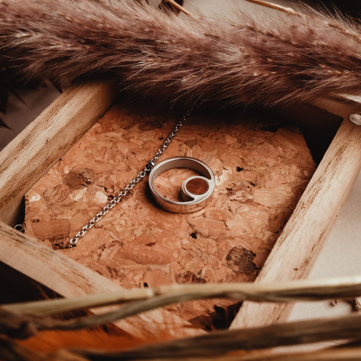 Collana "Pigment Collana" con legno di koa e argento, presentata in un ambiente elegante e rustico.