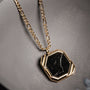 Collana "Scalar" presenta un audace pendente in marmo esagonale con accenti in oro, offrendo un look moderno e sofisticato.